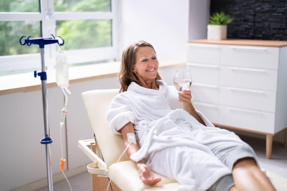 Smiling Woman Drinking Water Enjoying IV Therapy