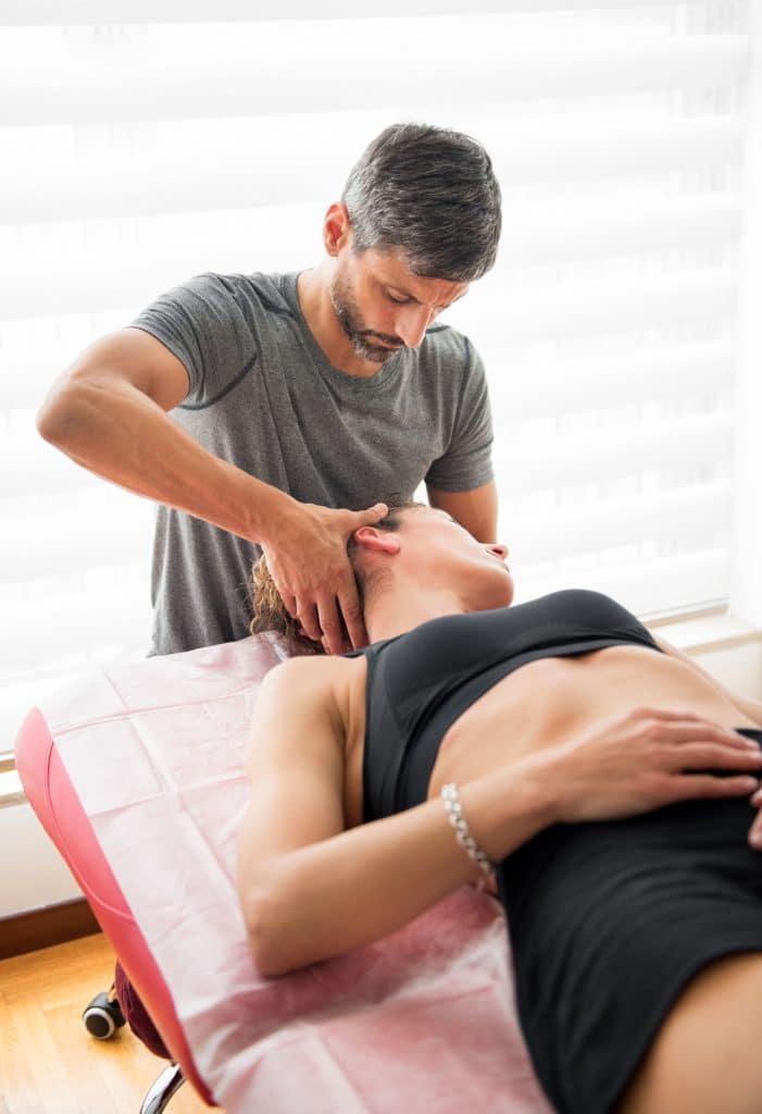 Male Osteopath Performing Cervical Trust Therapy On The Neck Of A Young Female Patient In His Practice During A Consultation In An Alternative Medicine And Healthcare Concept